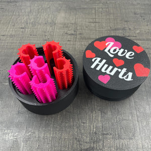 Een set van zes shibari rope spikes in een doosje met de tekst "Love Hurts"