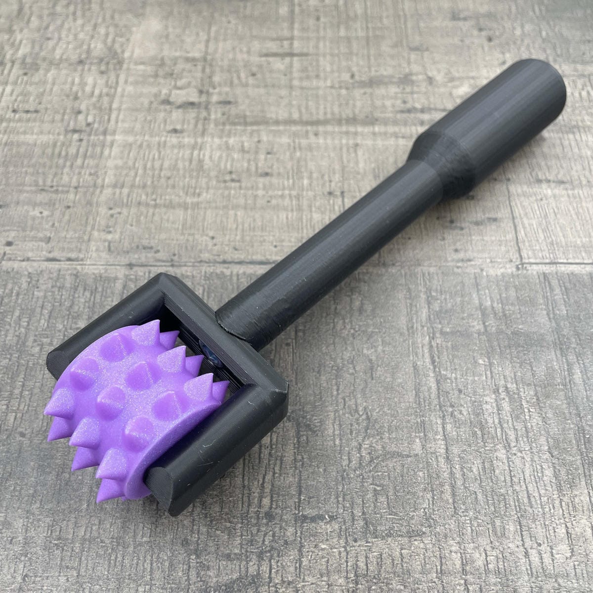 Een BDSM pinwheel met een zwart handvat en een paars wieltje