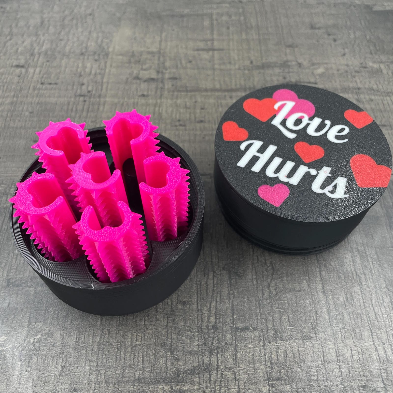 Een set van zes roze shibari rope spikes in een doosje met de tekst "Love Hurts"