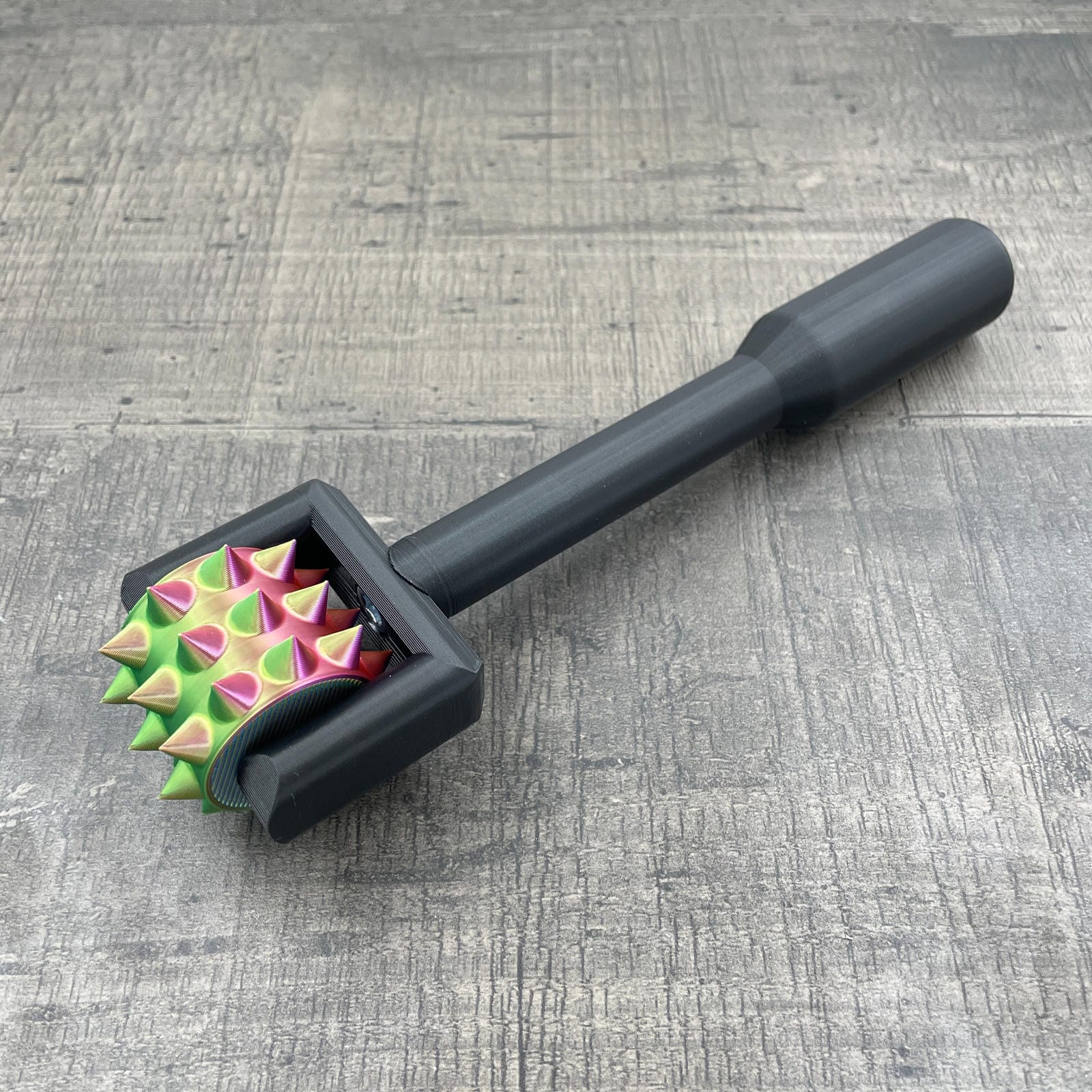 Een BDSM pinwheel met een zwart handvat en een wieltje in regenboog kleuren