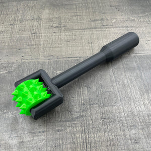 Een BDSM pinwheel met een zwart handvat en een groen wieltje