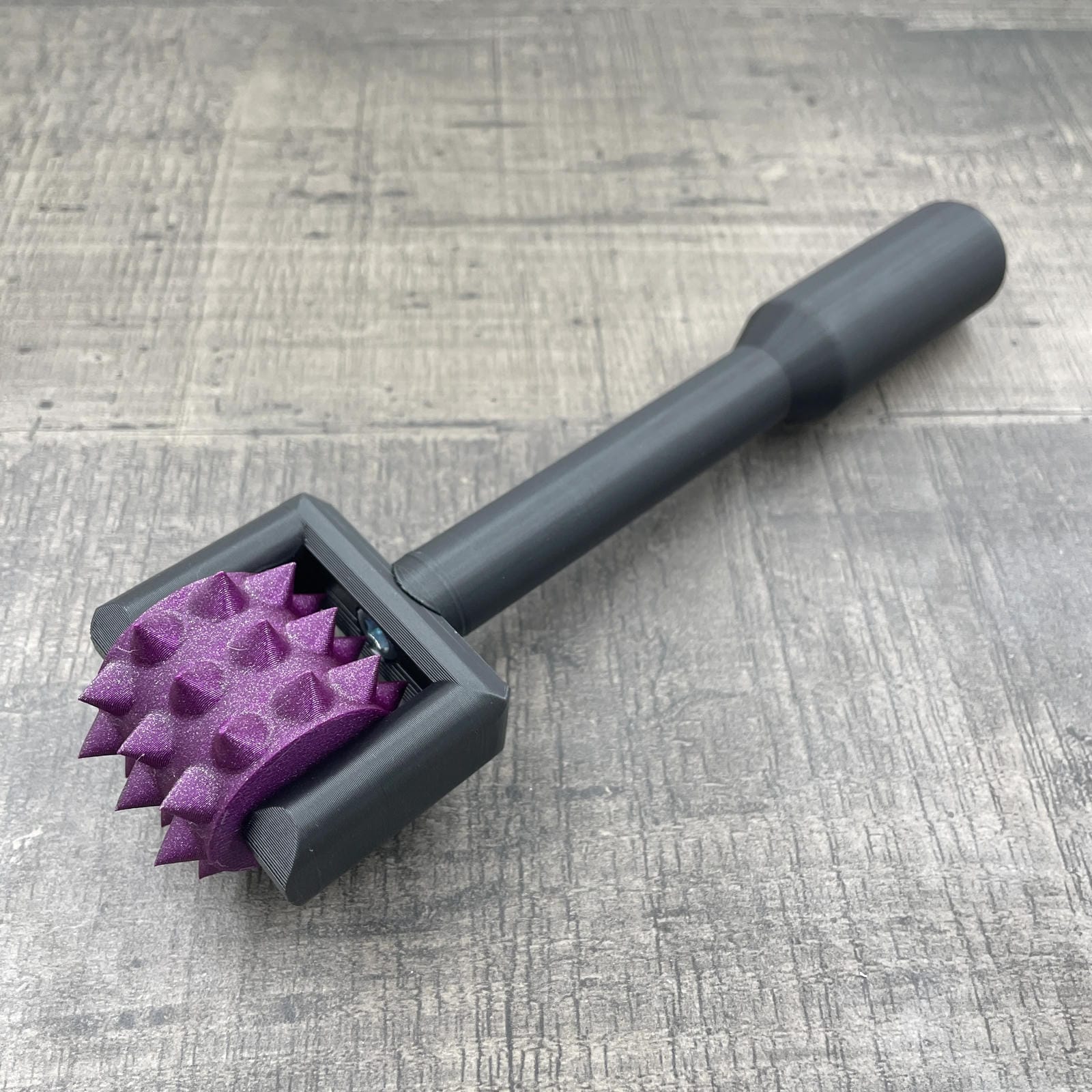 Een BDSM pinwheel met een zwart handvat en een paars wieltje met glitters