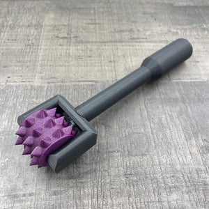 Een BDSM pinwheel met een zwart handvat en een paars wieltje met glitters