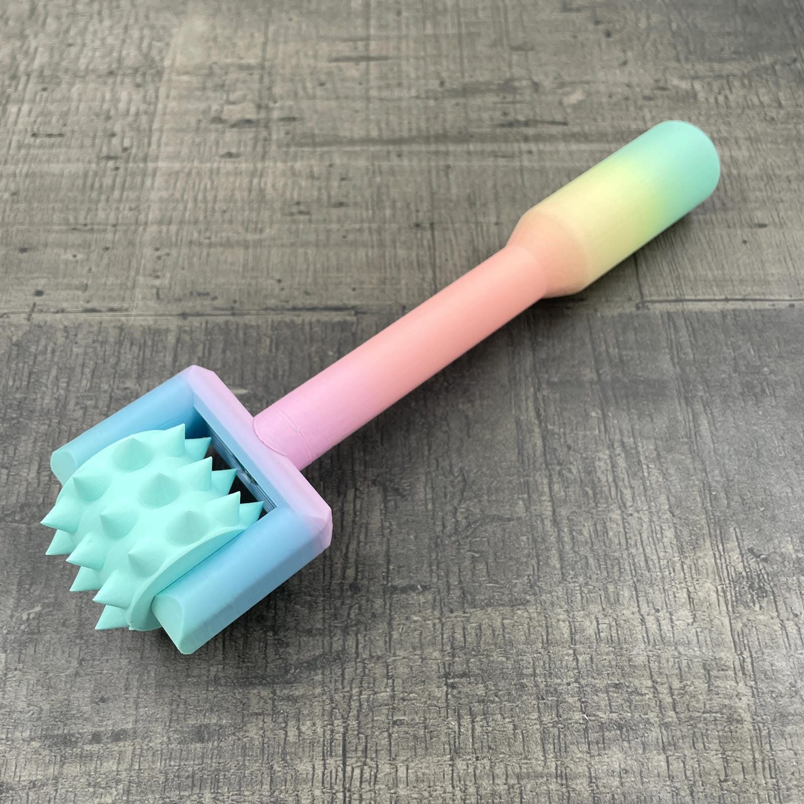 Een BDSM pinwheel met een pastel-kleurig regenboog handvat en een mint-kleurig wieltje