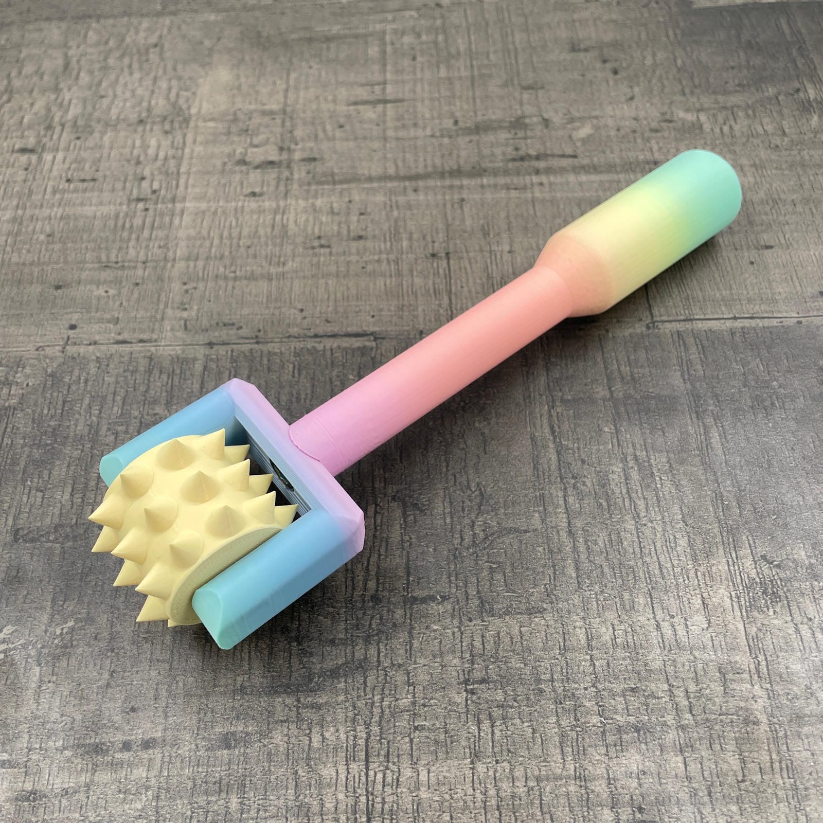 Een BDSM pinwheel met een pastel-kleurig regenboog handvat en een geel wieltje