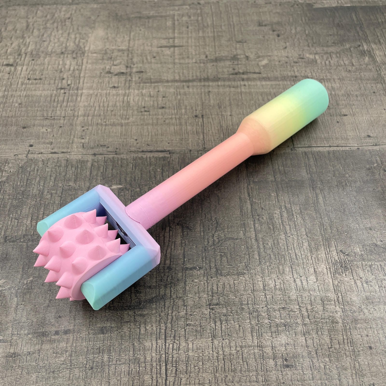 Een BDSM pinwheel met een pastel-kleurig regenboog handvat en een roze wieltje