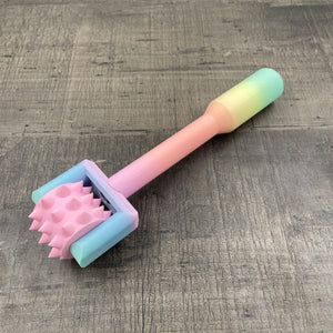 Een BDSM pinwheel met een pastel-kleurig regenboog handvat en een roze wieltje