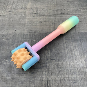 Een BDSM pinwheel met een pastel-kleurig regenboog handvat en een oranje wieltje