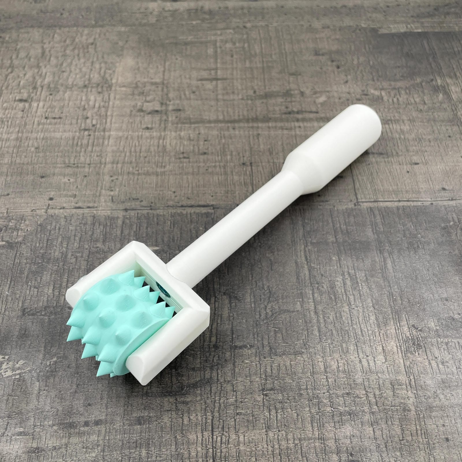 Een BDSM pinwheel met een wit handvat en een mint-kleurig wieltje