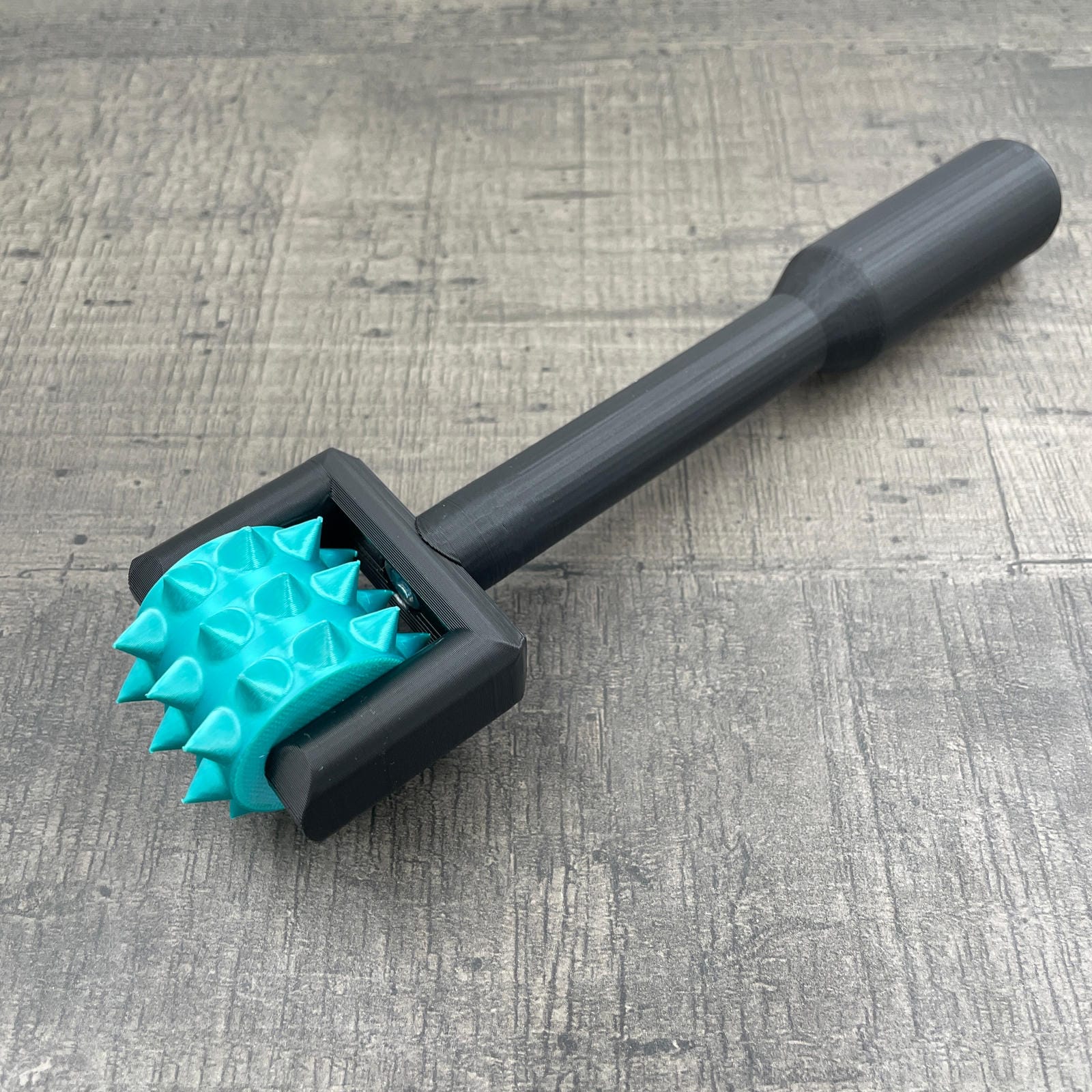 Een BDSM pinwheel met een zwart handvat en turquoise wieltje