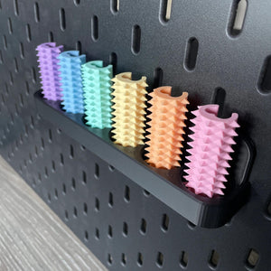 Een doosje met zes shibari rope spikes in regenboog kleuren voor de Ikea Skadis