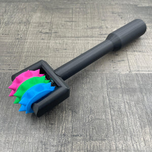 Een BDSM pinwheel met een zwart handvat en wieltje in de kleuren van pan-seksuele vlag